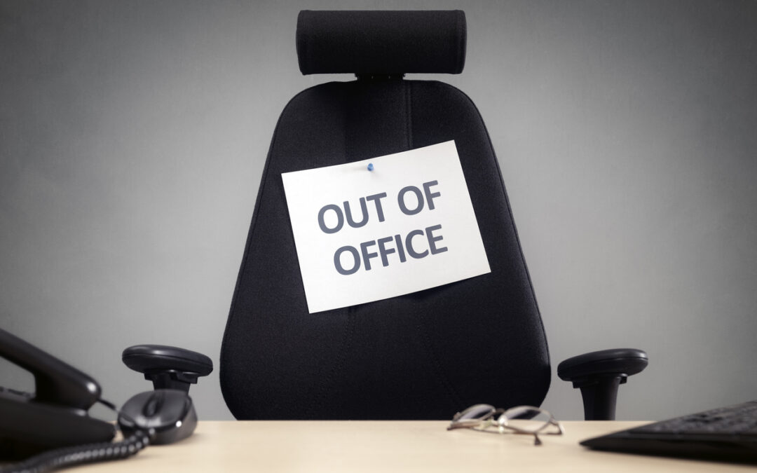 Bürostuhl und Schreibtisch. An dem Stuhl klebt ein Zettel mit der Aufschrift "Out of Office"